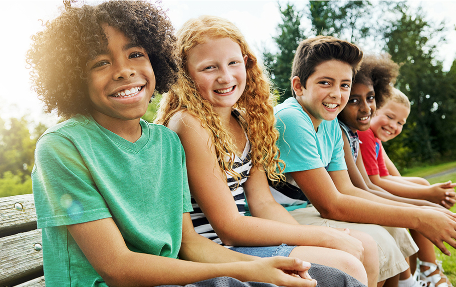 diverse group of kids sitting in a row smiling